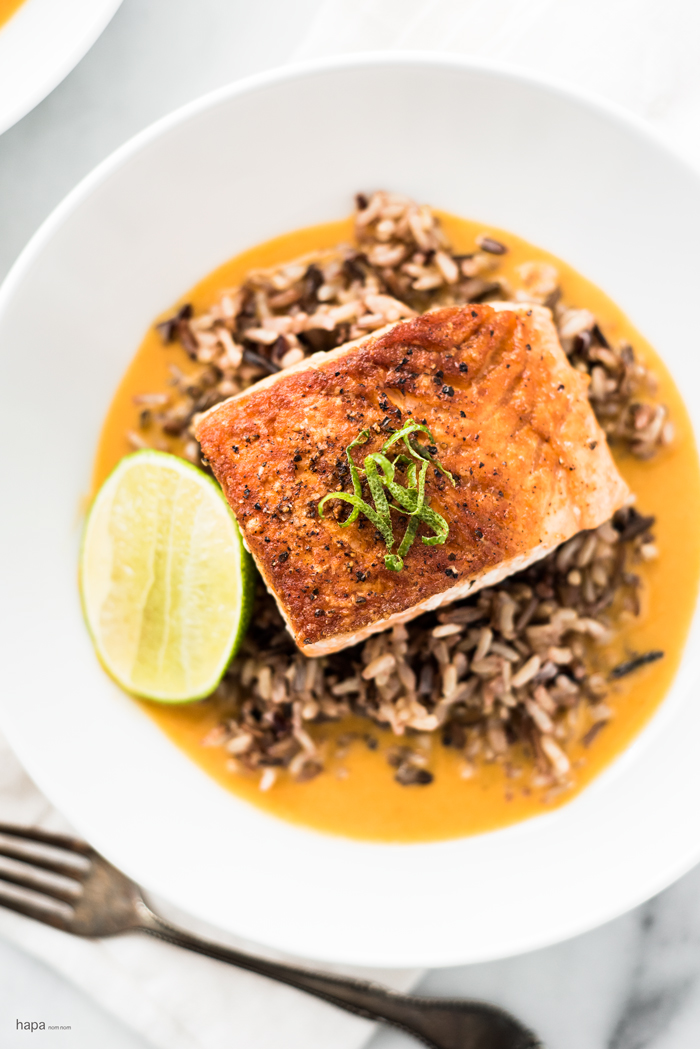 Pan seared salmon on a bed of wild rice in a rich and creamy ginger and coconut curry broth.