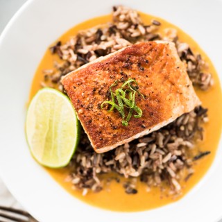 Pan seared salmon on a bed of wild rice in a rich and creamy ginger and coconut curry broth.